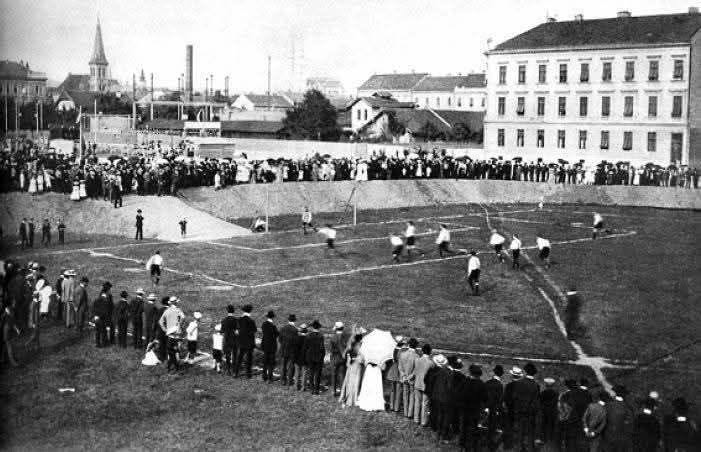 Prva javna nogometna utakmica u Hrvatskoj, Marulićev trg 1906. godine. U pozadini Plinara sa dimnjakom- iza nje toranj Evangelističke crkve